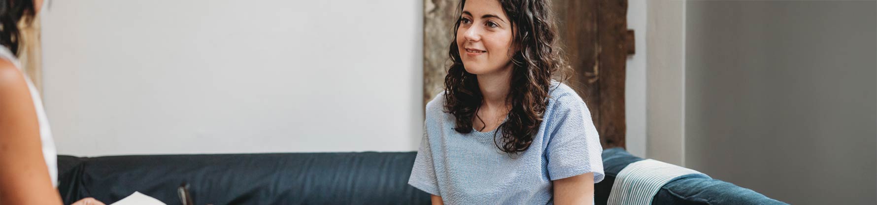 Ein Mädchen sitzt auf dem Sofa und redet mit einer Psychologin